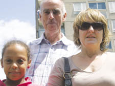 Jetta Oliner with her daughter Grace and partner Alan Nugent with the fire-damaged flats in the tower block behind them