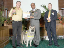 A triumphant Sean Kanavan, with his dog Khara, receives his Camden In Bloom award from Mayor Omar Faruque Ansari and Camden Council’s head of street policy Sam Monck at the Town Hall prize-giving ceremony on Monday