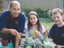 Park rangers Bhupesh Thapa and Dave Bamford help eight-year-old Valetina Parilli tend to her new plant at St Mary's Church Gardens