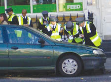 Traffic wardens gather round the car in Clerkenwell Green.