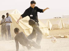 Tom playing football with children at a refugee camp in Jordan